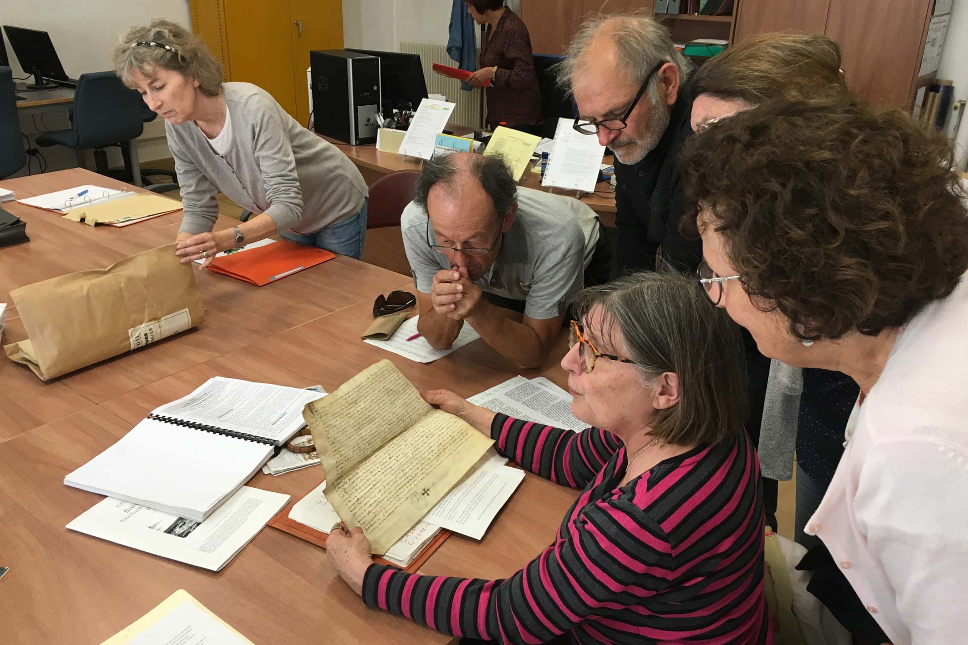 Gérard, Marie-Thérèse, Geneviève, Alain, Robert, Michel et Marinette se retrouvent tous les mois aux Archives municipales autour de vieux documents à décrypter.